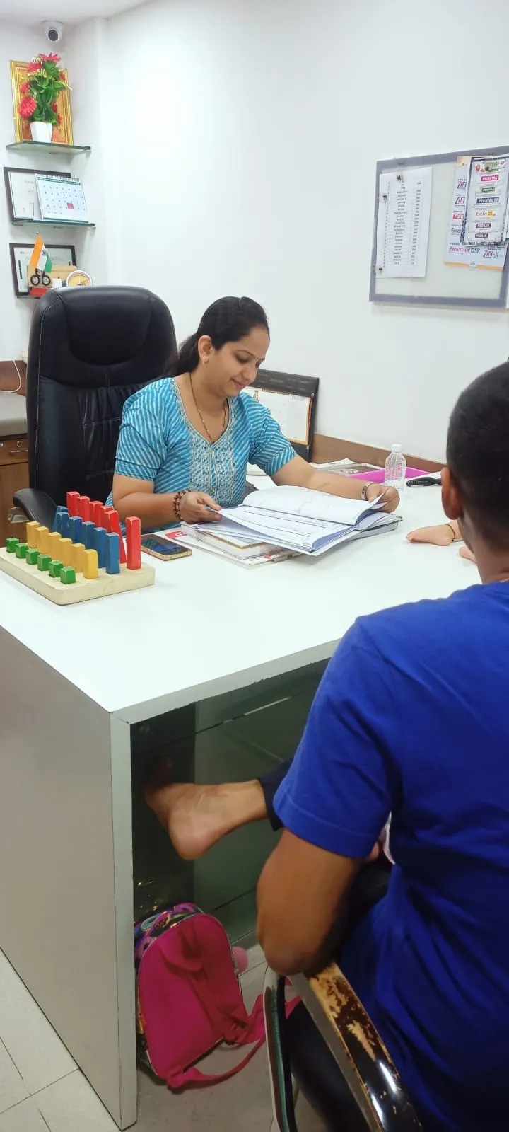 Dr. Meghna Oza writing notes at her desk in a physiotherapy centre
