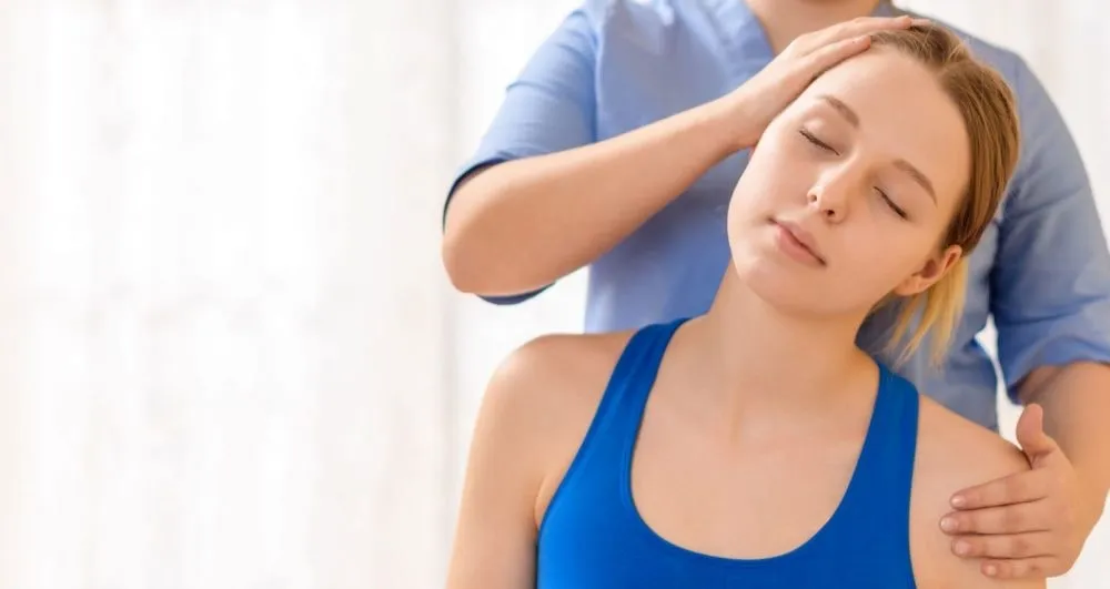Physiotherapist easing tight neck and shoulder muscles of a woman