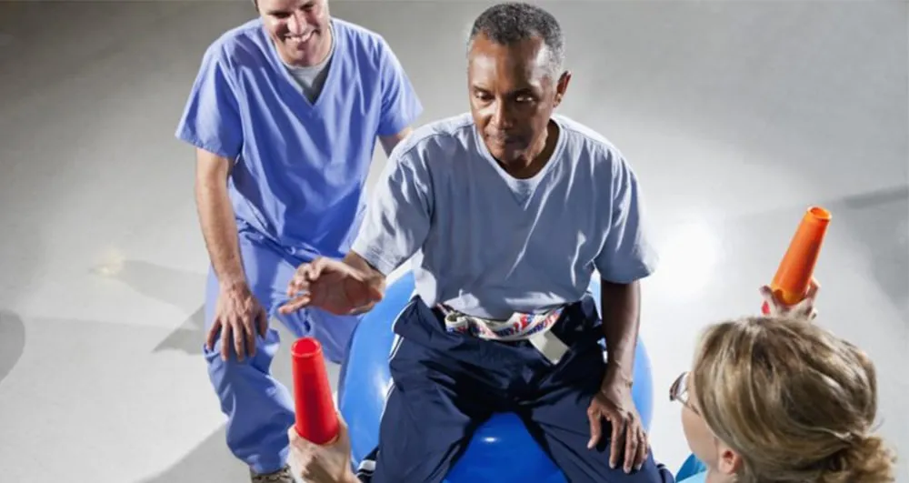 Older man doing balance and arm exercises with therapists in a rehabilitation gym