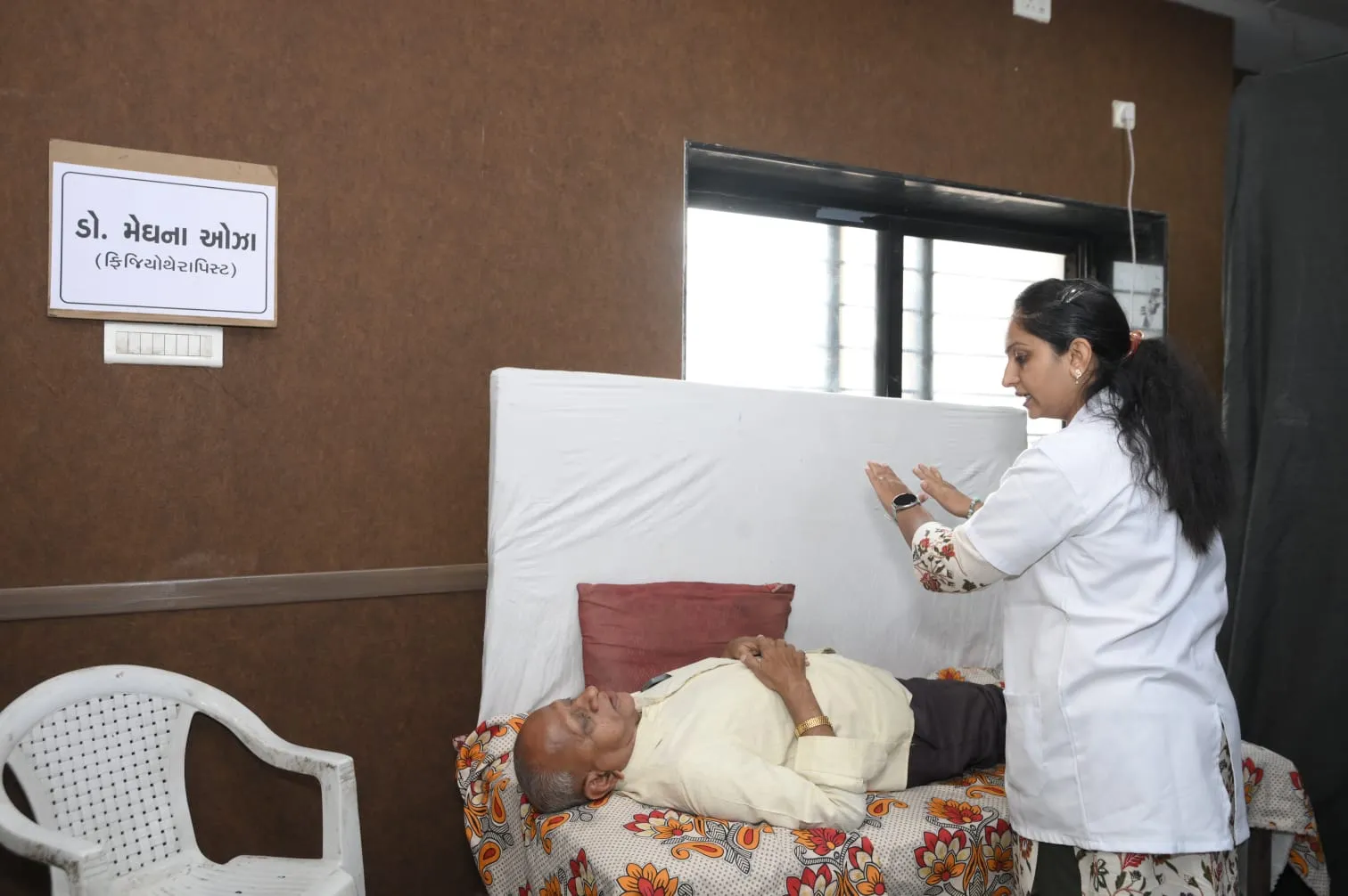 Dr. Meghna Oza assessing a patient lying on a treatment bed at a health camp